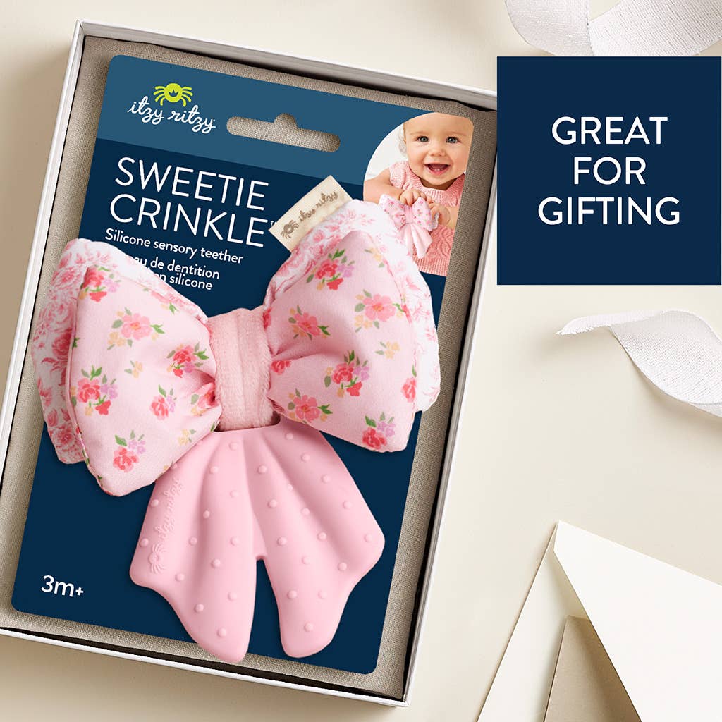 Pink crinkle teether with floral design in packaging, labeled 'Sweetie Crinkle' by itzy ritzy.