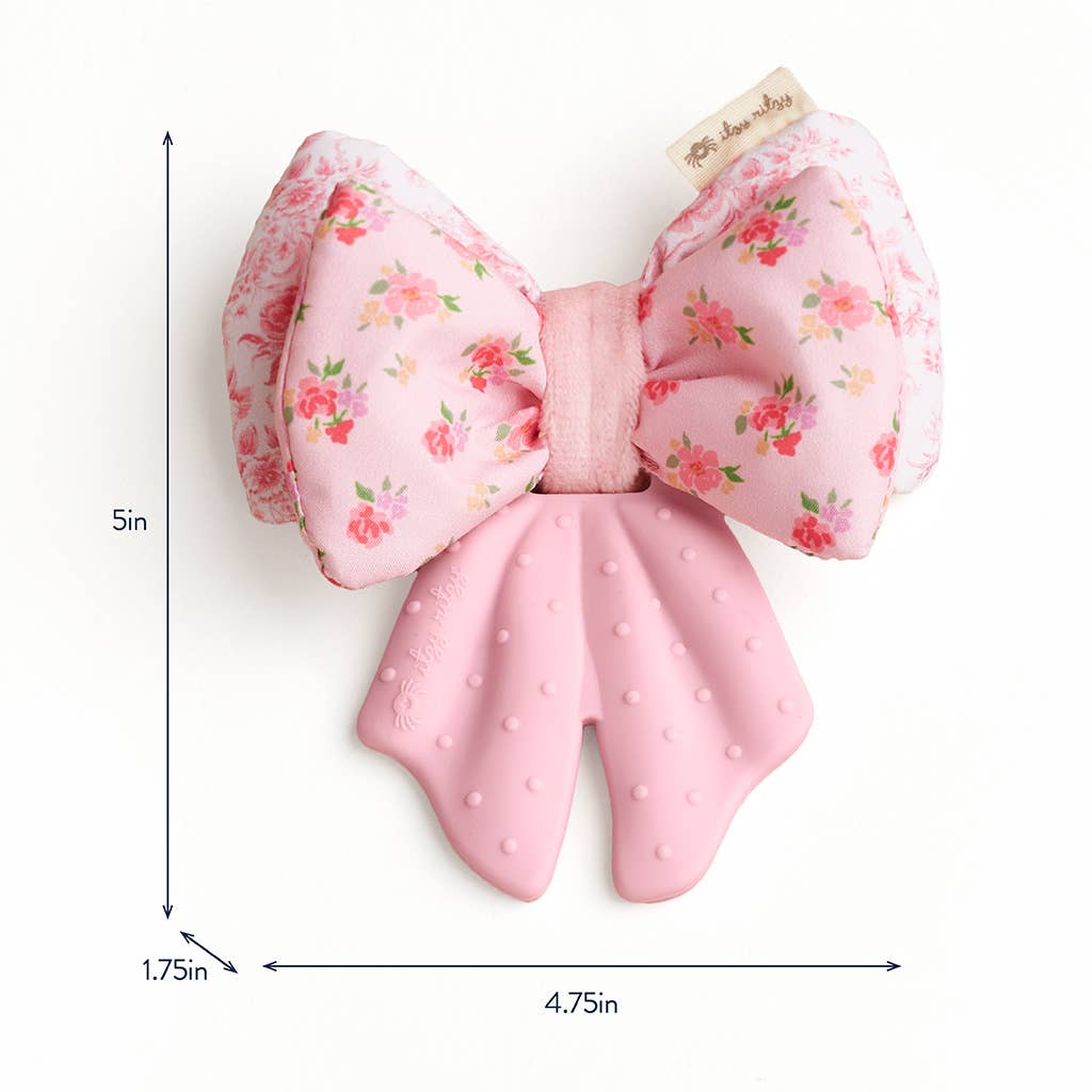 Pink bow-shaped crinkle teether with floral pattern and measurements on a white background
