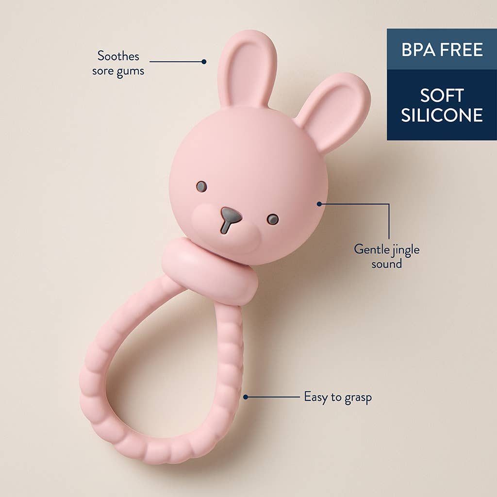 Pink bunny-shaped rattle with text on a beige background