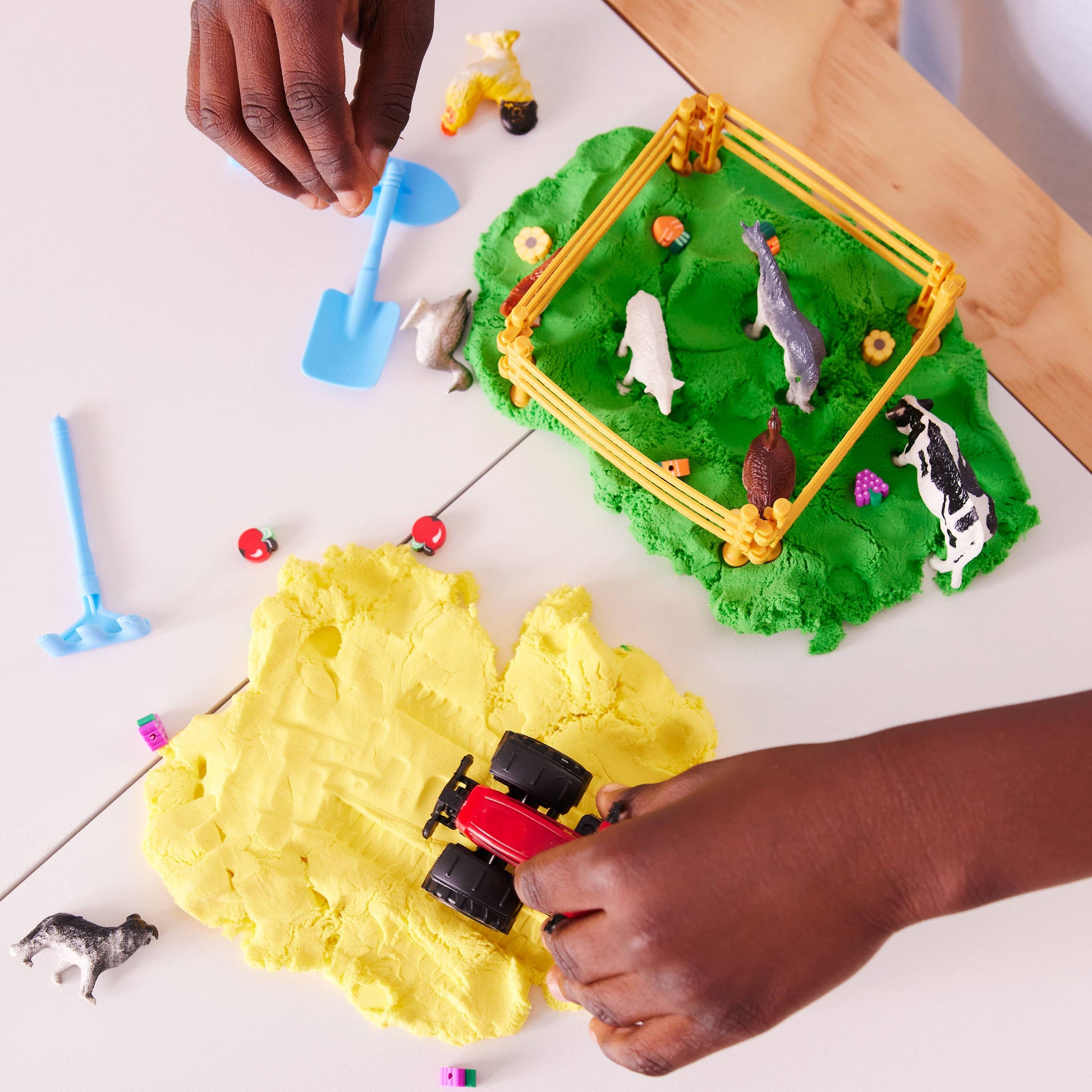 Children playing with play dough and toys on a white surface