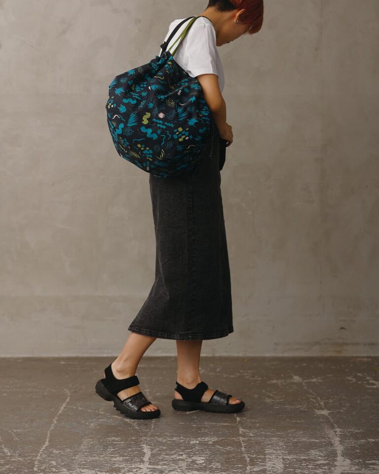 Person wearing a blue floral drawstring bag against a plain background