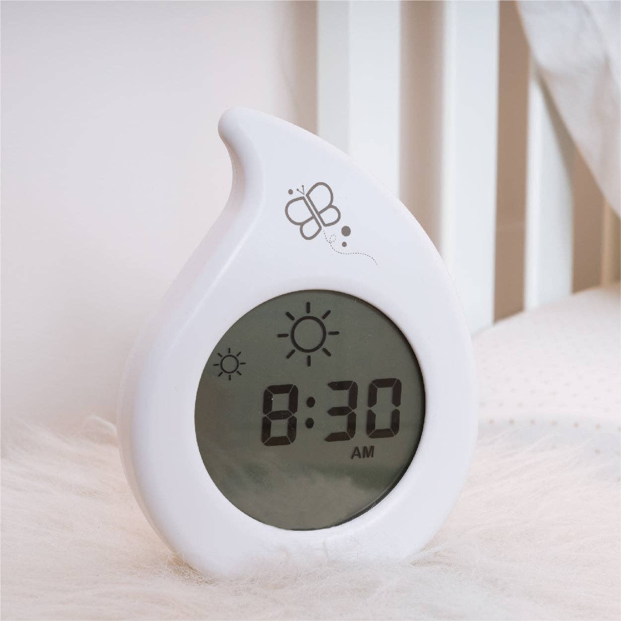 White digital clock with butterfly design on a soft surface